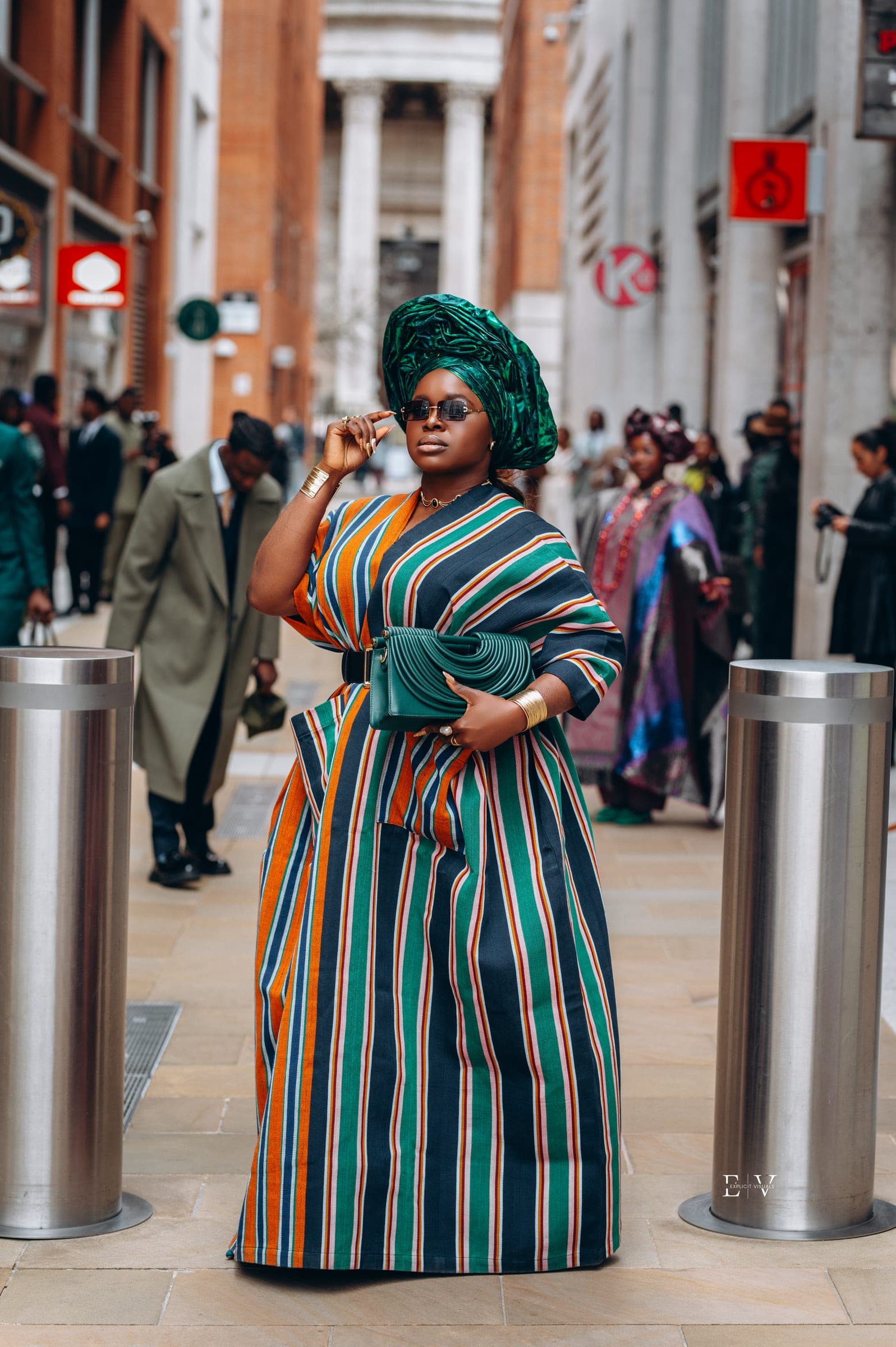 The same look turned slightly away, a hand at her chin and a pleated green clutch held against her waist.