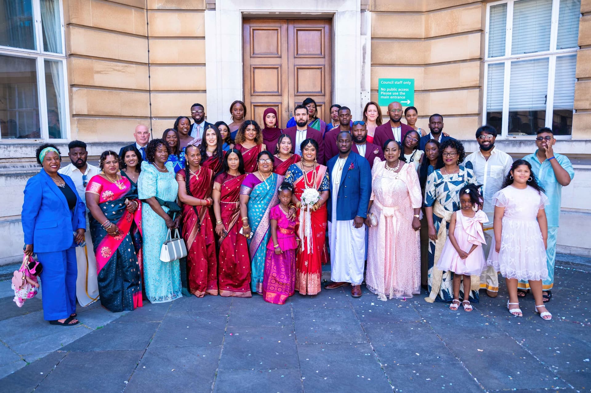 The same group portrait framed wider, confetti still scattered across the paving.