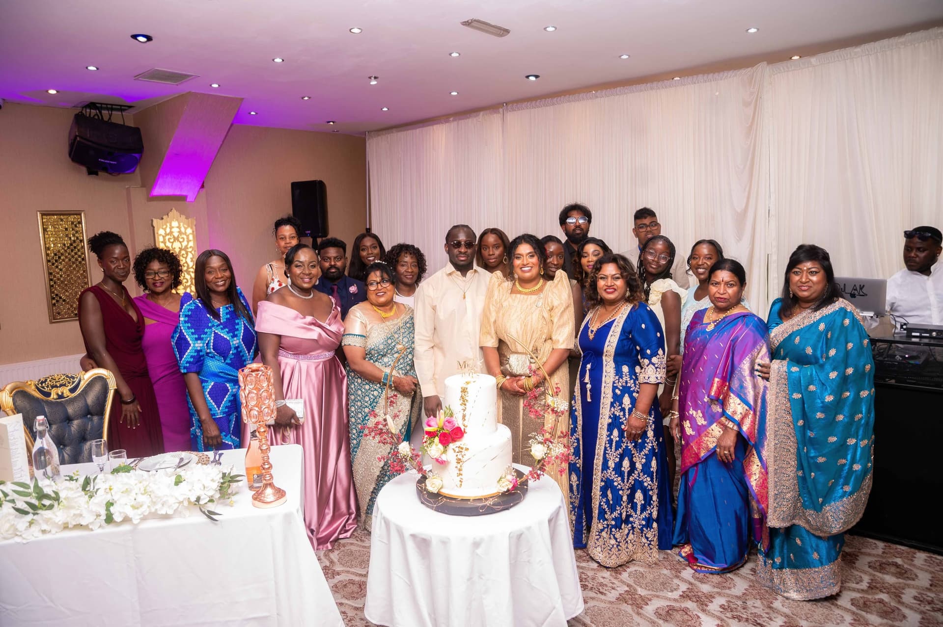 Guests crowd in around the cake table for a group portrait at the reception.