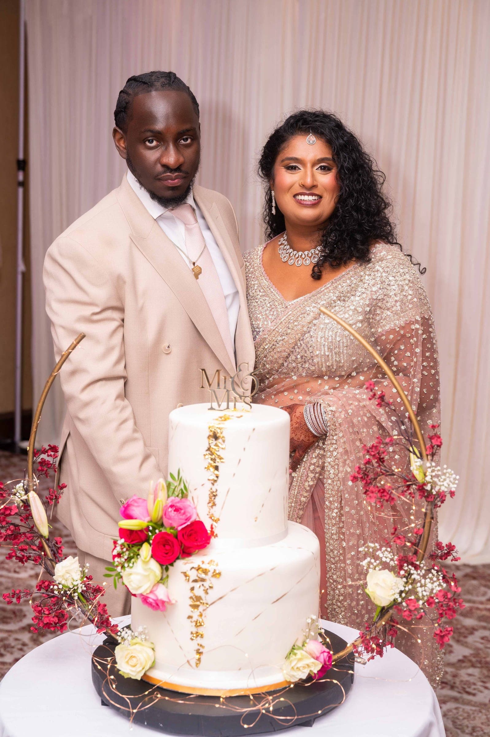 A third change of outfit beside the cake — a cream suit and a blush sequinned saree.