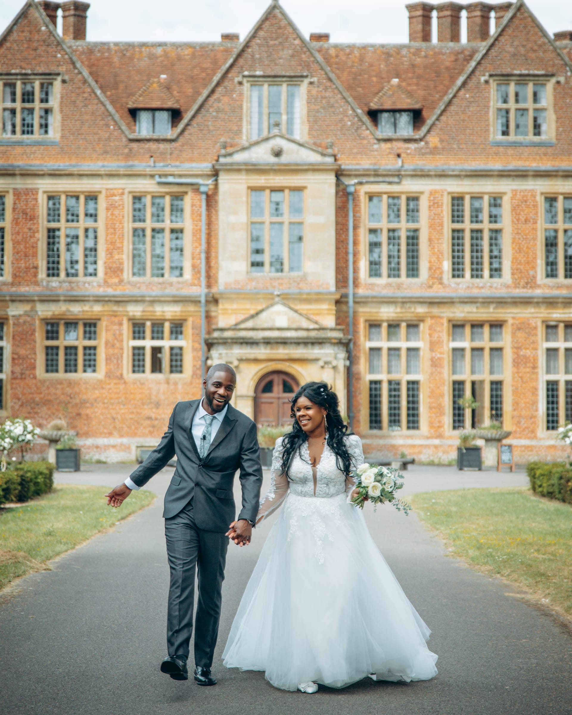 The same walk with both of them laughing, her lace sleeves and full tulle skirt bright against the brick.