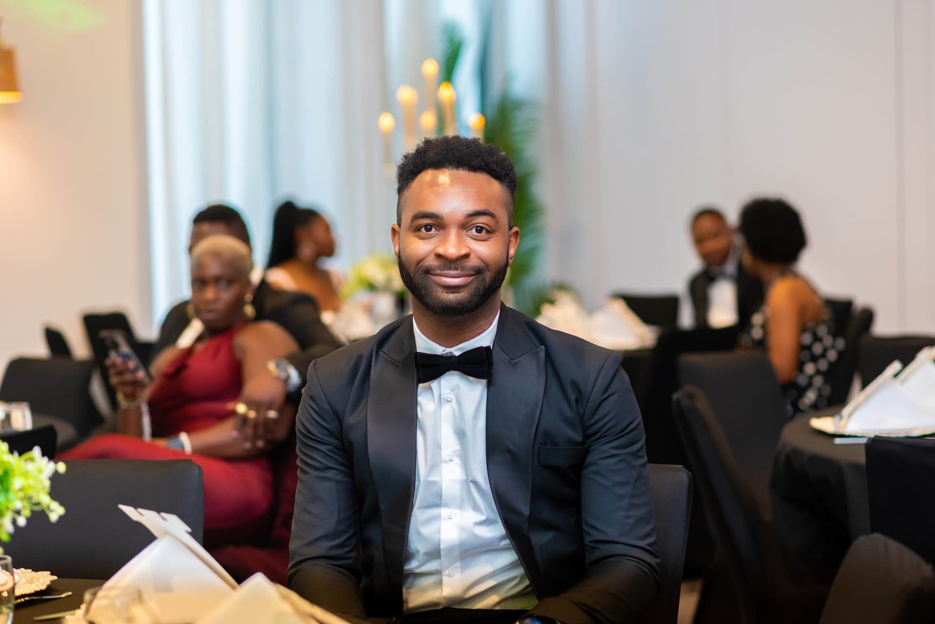 A guest turns from his table with a smile between courses, the room and other tables falling out of focus behind him.